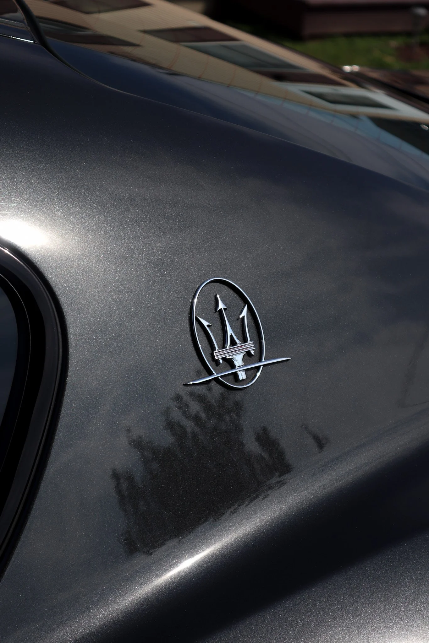 Close-up of a black Maserati car hood with a silver Maserati emblem.