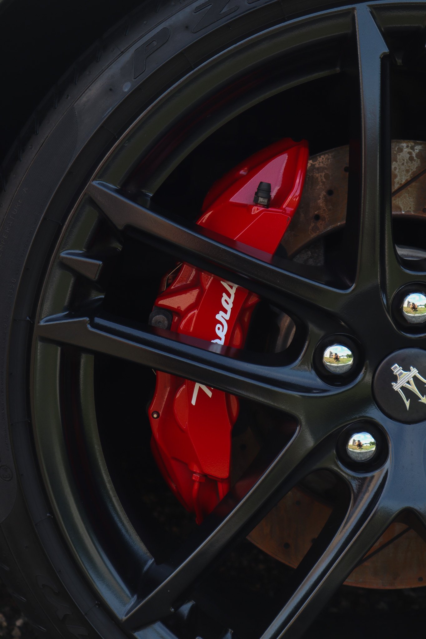 Close-up of a car wheel with a black rim and a bright red caliper behind it, with the word 'Speed' partially visible on the caliper.