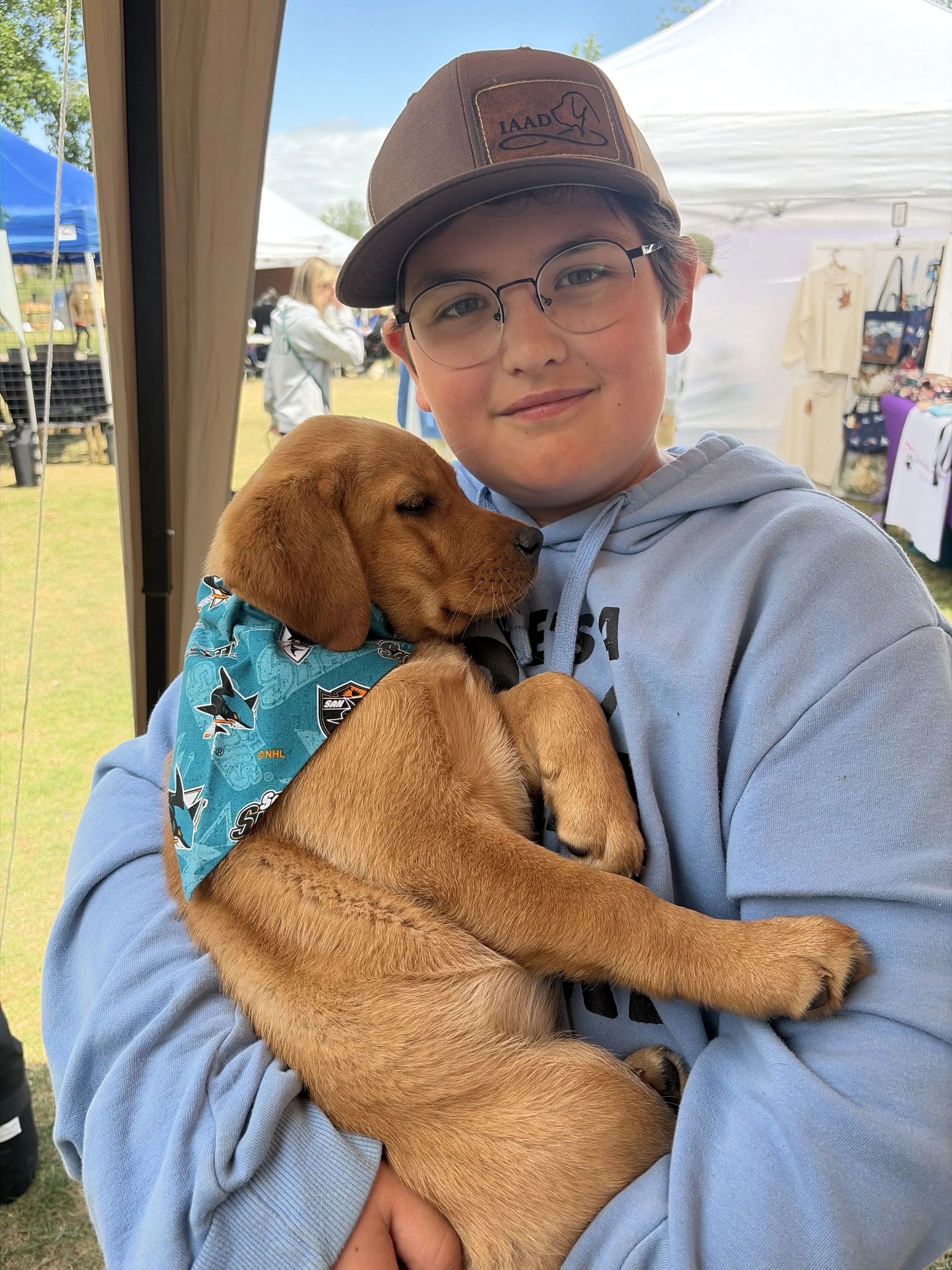 Young IAAD supporter holding an assistance dog puppy at a community event.