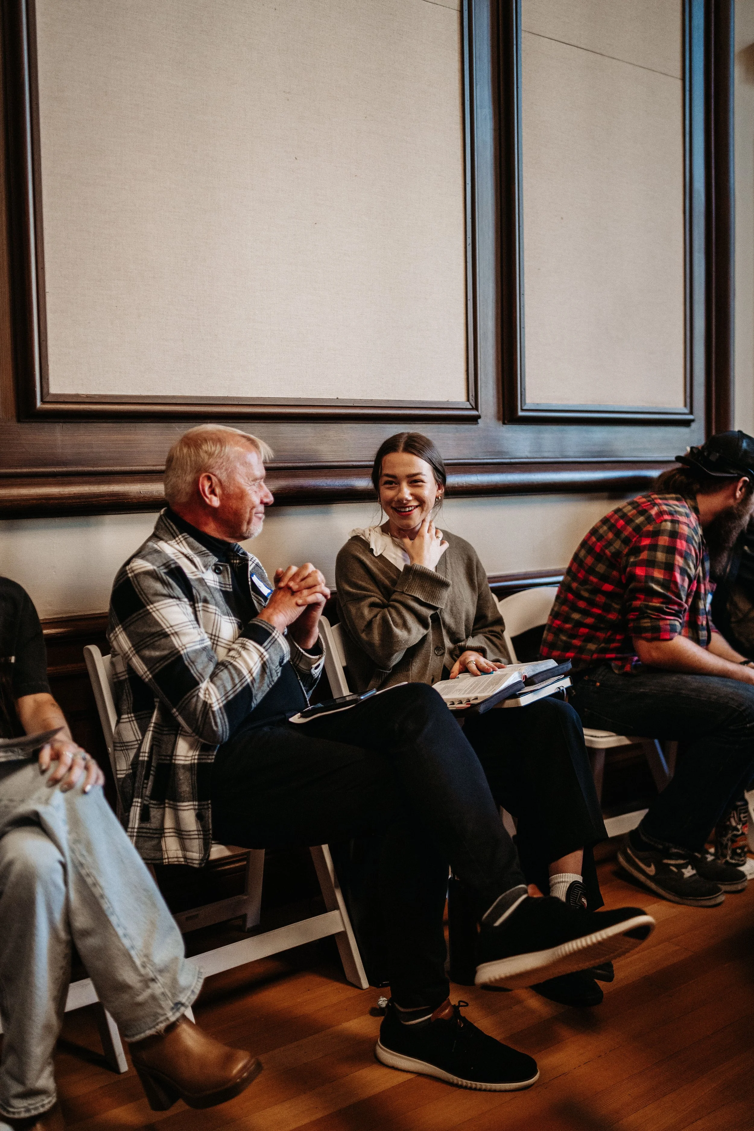 People sitting in a row of chairs, engaged in conversation and smiling.