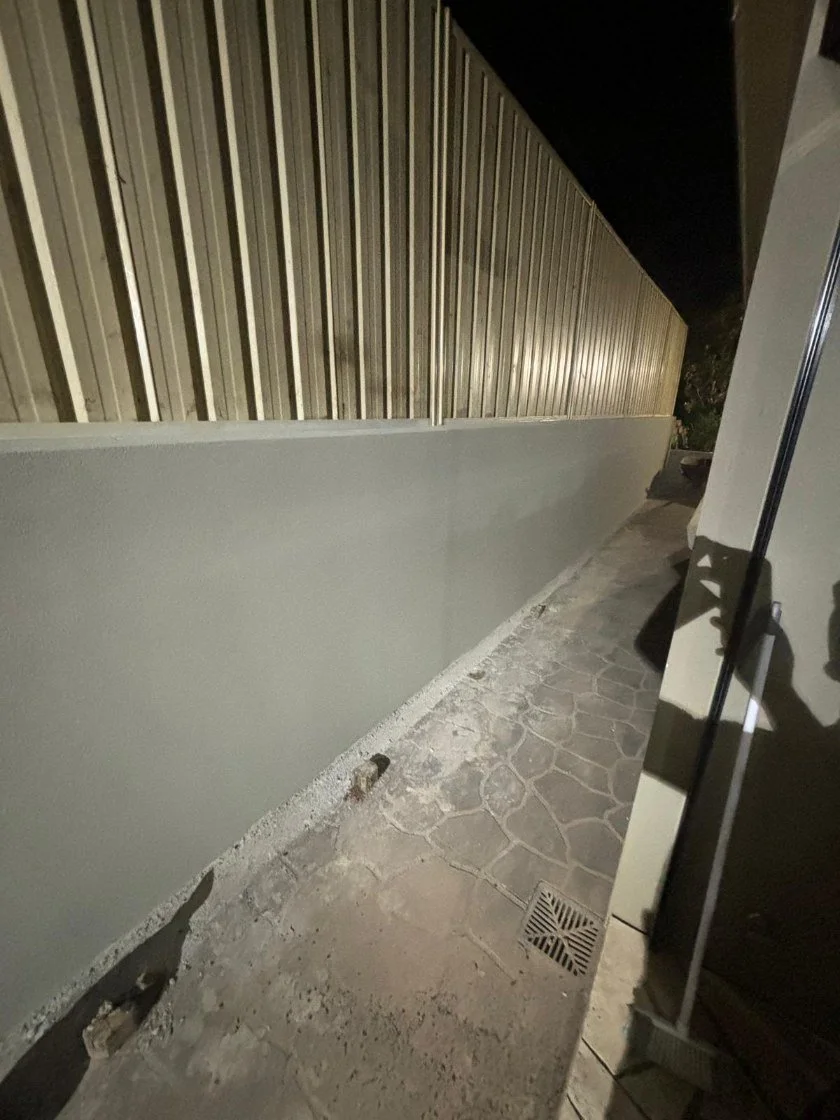 Grey concrete retaining wall along narrow side passage in Sydney