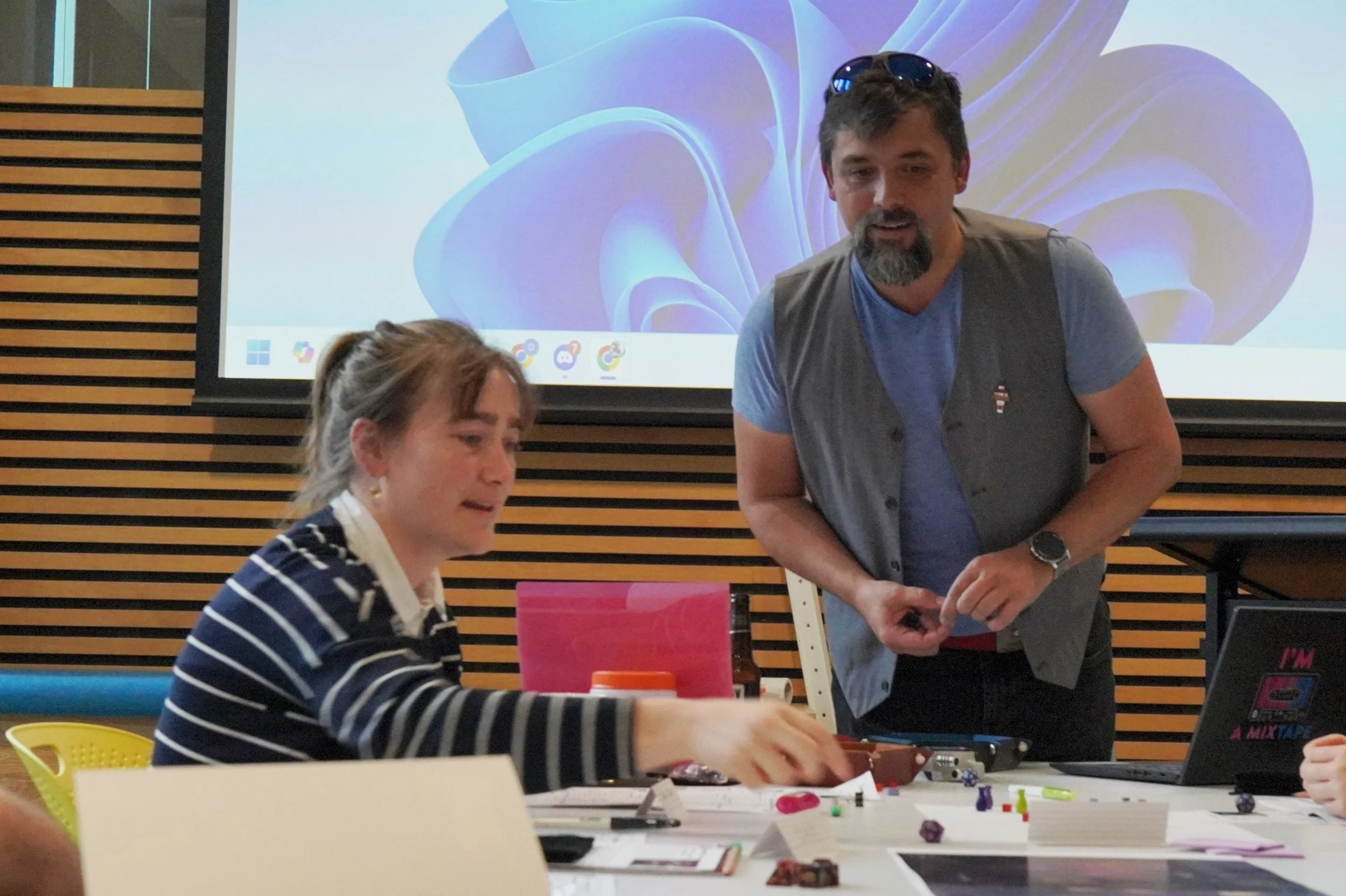 People enjoying a workshop with a projector displaying an abstract design in the background.