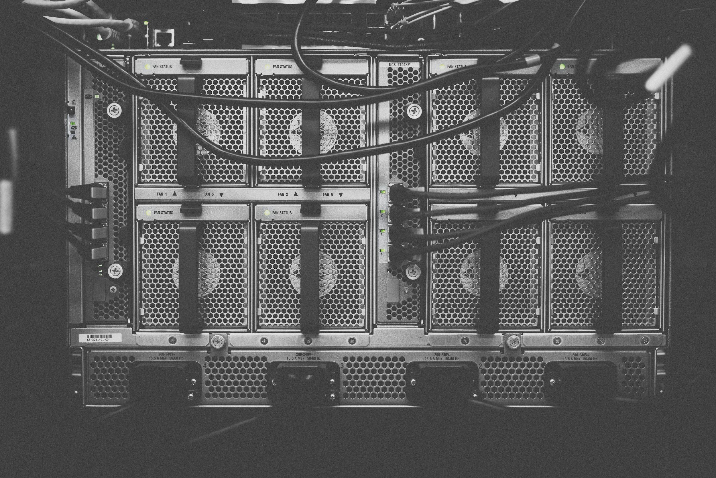 Front view of a server rack with multiple cooling fans and network cables, mostly in black and white.