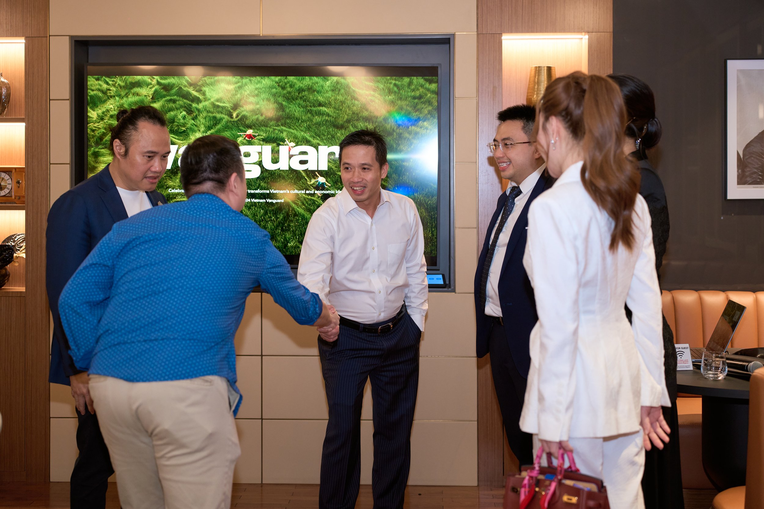 Group of people in a meeting room shaking hands and smiling.