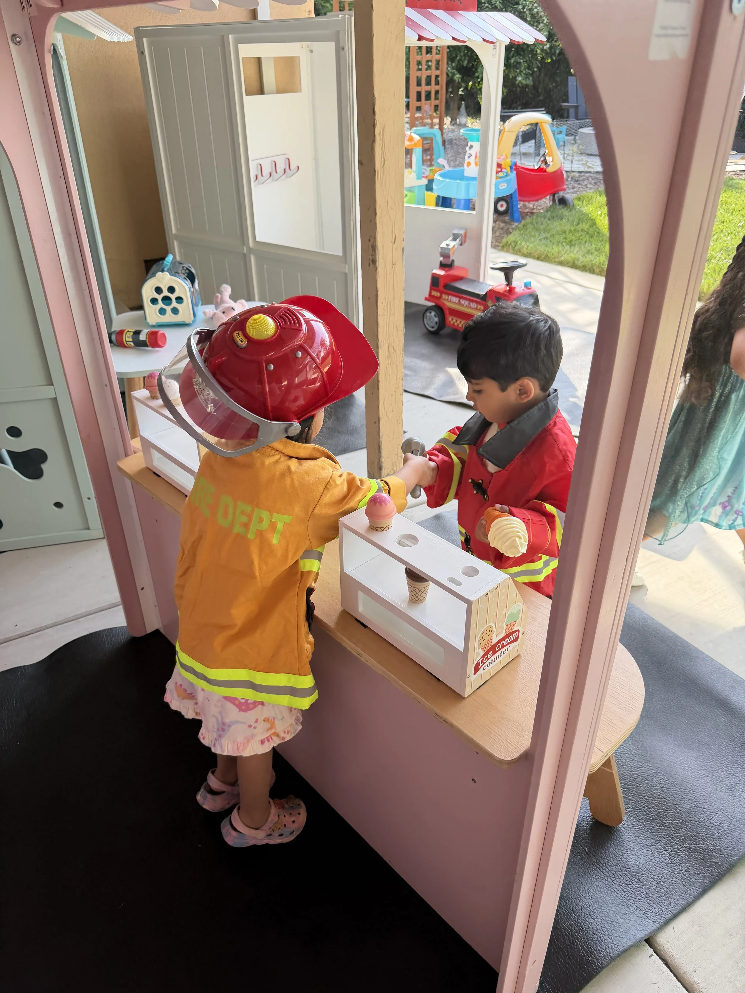 Kids in firefighter costume playing in a pretend ice cream shop