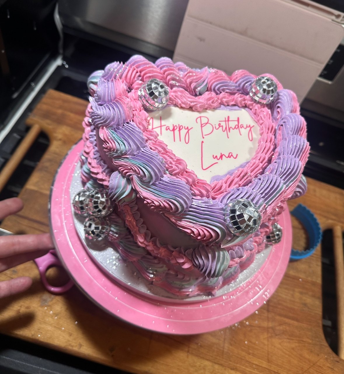 Pink and purple disco-inspired heart-shaped birthday cake with piped vintage buttercream swirls and mini mirror ball accents — custom design by Twice As Sweet OC in Huntington Beach