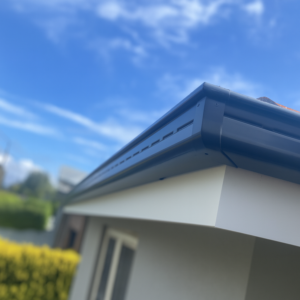Close-up of a house's roof and gutter against a blue sky with some clouds, shot from below.
