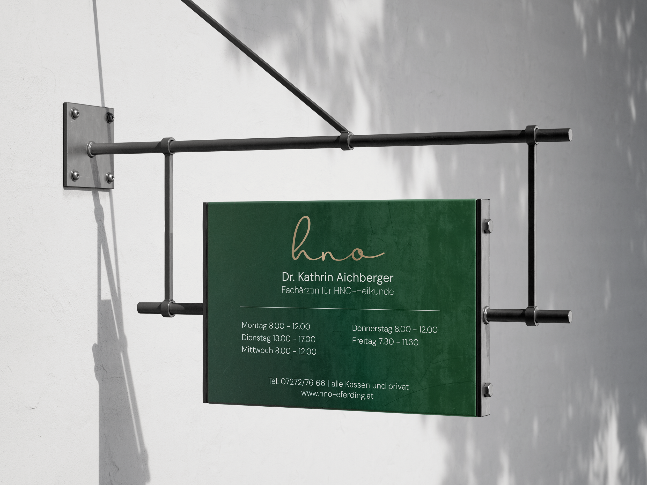 Praxis-Schild von Dr. Kathrin Aichberger, Fachärztin für HNO-Heilkunde, mit Öffnungszeiten und Kontaktinformationen, an einer Wand montiert.