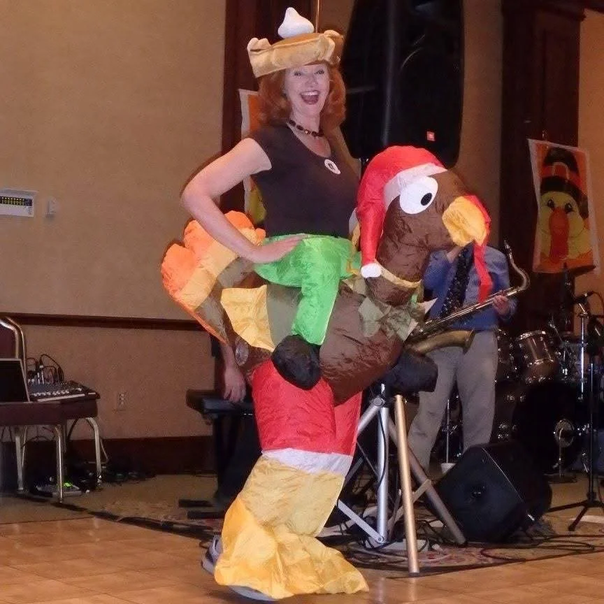 Person wearing a turkey costume at a Thanksgiving-themed event.