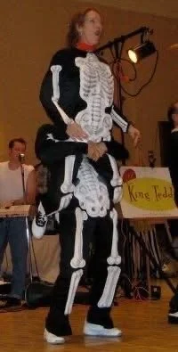Two people in a creative skeleton costume performing at an indoor event.