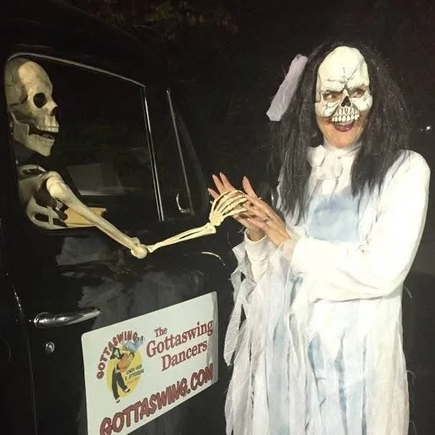 Halloween scene with person in skeleton costume and skeleton figure in car