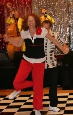 Couple dancing on checkered floor with a live band in the background.