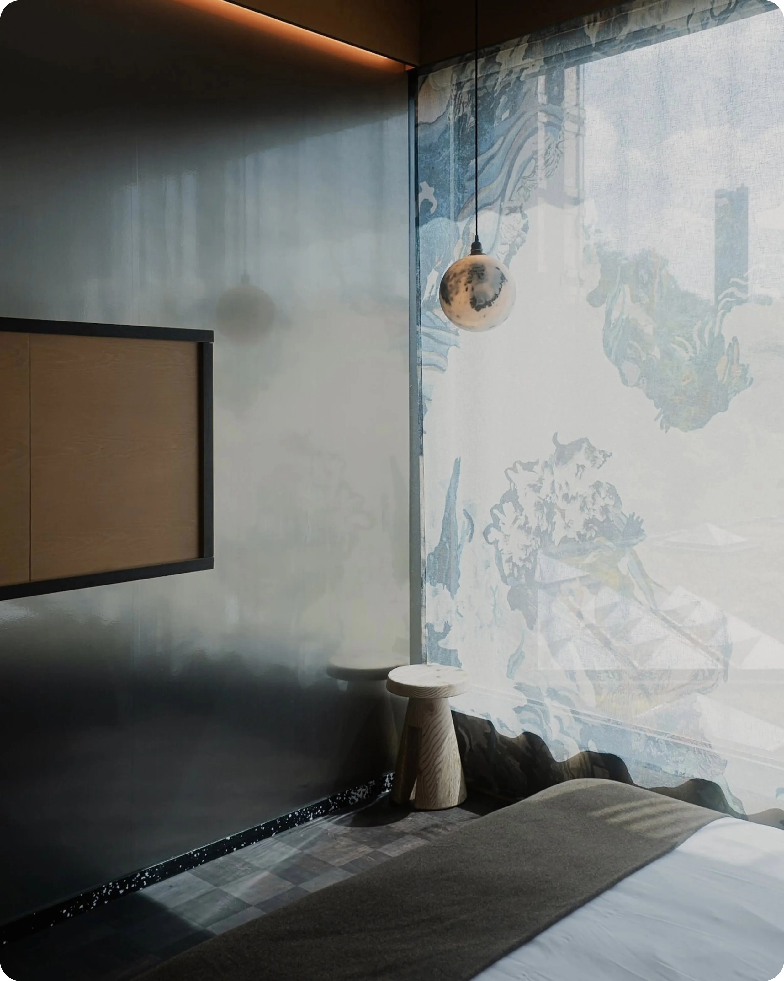 Photo d'aspect professionel clair obscur d'un coin de chambre du Mix Hotel à Bruxelles avec mur en alu, lampe suspendue en forme de lune, tabouret en bois, et fenêtre avec une voile de style asiatique ou orientale.