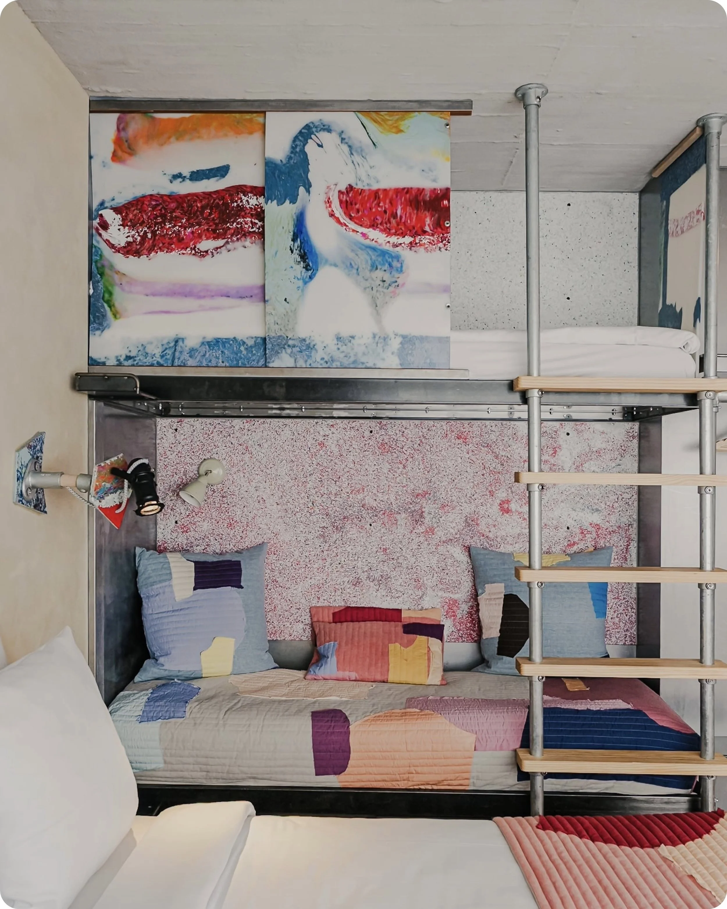 Photo d'aspect professionel d'une chambre du Jam Hotel à Bruxelles avec un lit superposé, décorée avec des panneaux en plastique recyclé colorés avec un lit double au sol en avant plan.