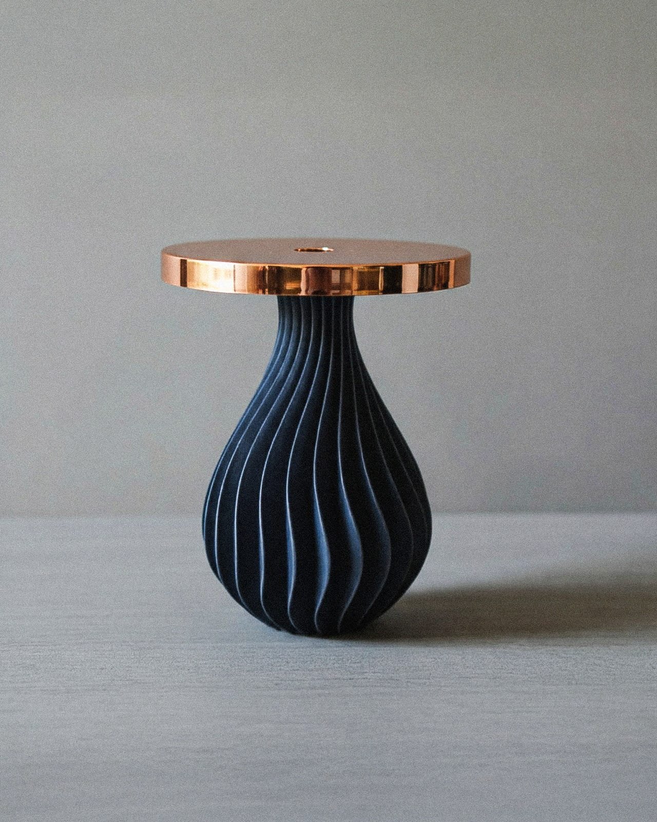 Tavolo con piano in ottone e base in legno intagliato a forma di goccia