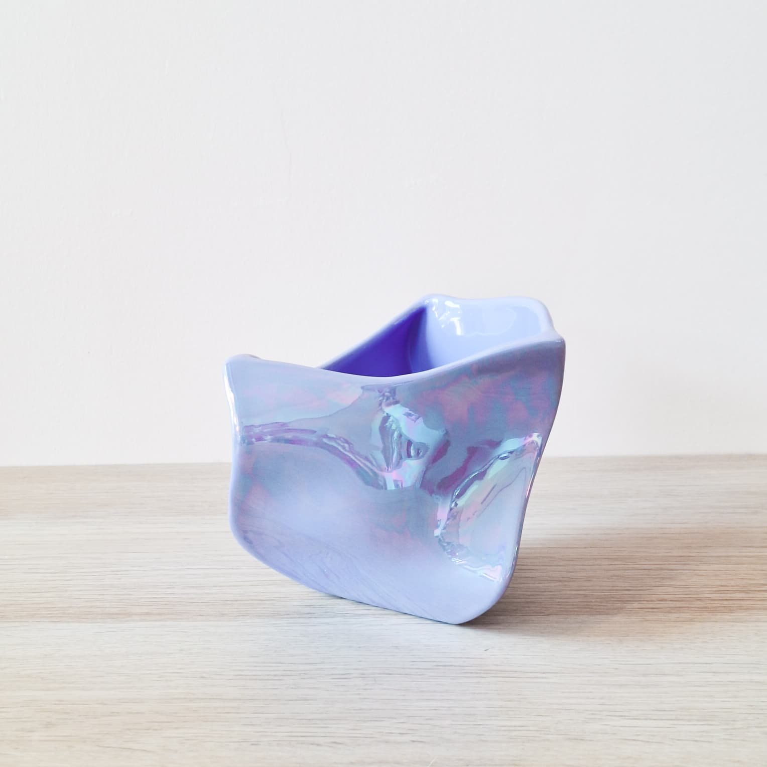 Una ciotola di porcellana iridescente su un tavolo di legno chiaro.