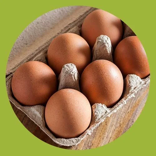 Six brown eggs in a cardboard egg carton on a wooden surface with a green border.