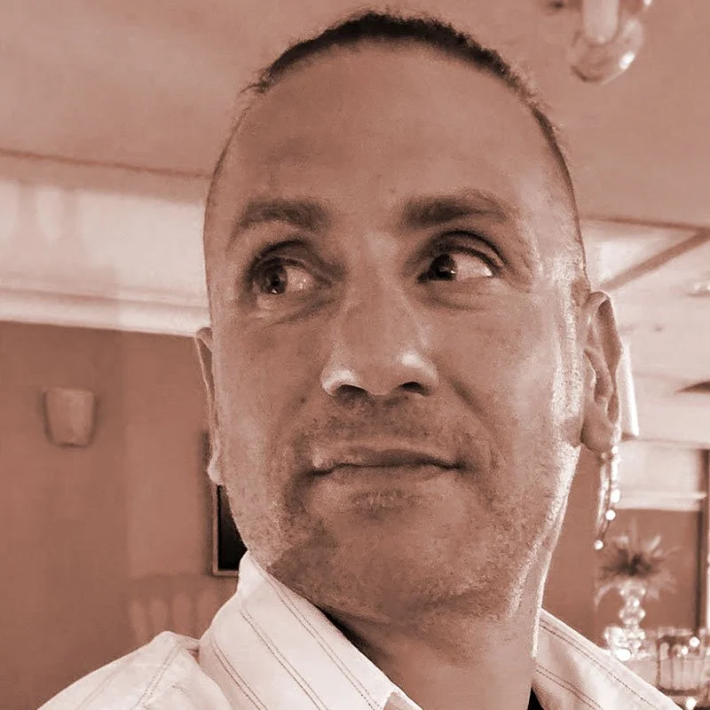 Man with short hair looking to his left in an indoor setting.