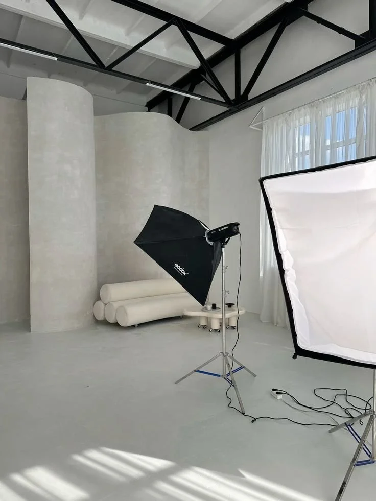Woman in beige outfit lounging on white sofa, holding a large pillow.