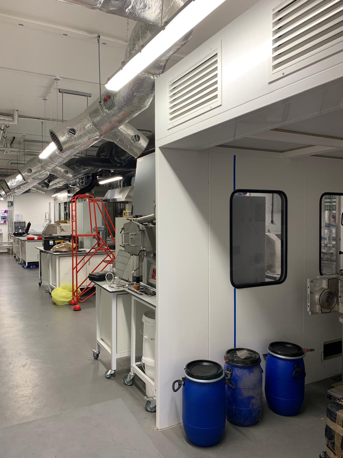 Industrial laboratory interior with equipment, ducts, and barrels.