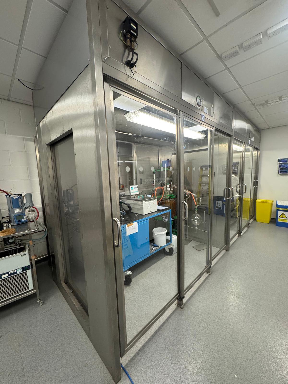 Laboratory fume hood with glass doors, laboratory equipment inside, and safety containers.