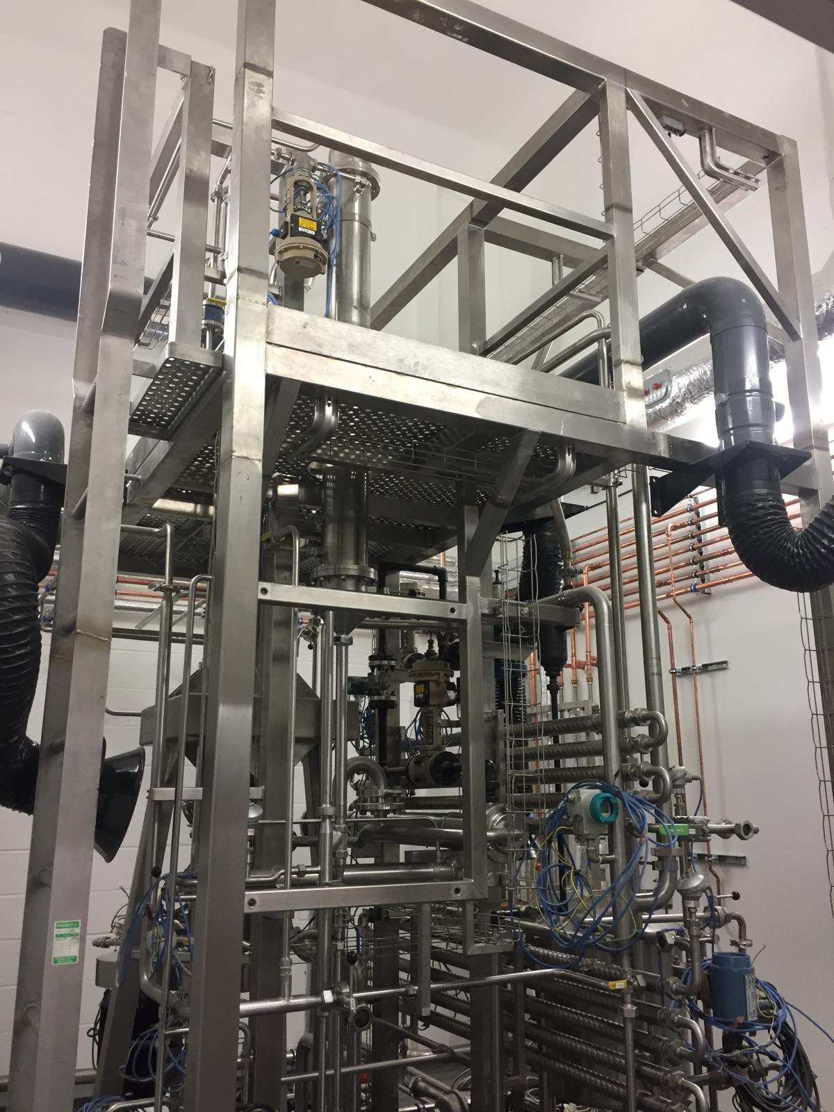 Industrial machinery with metal framework, pipes, and tubing, used for processing or manufacturing.