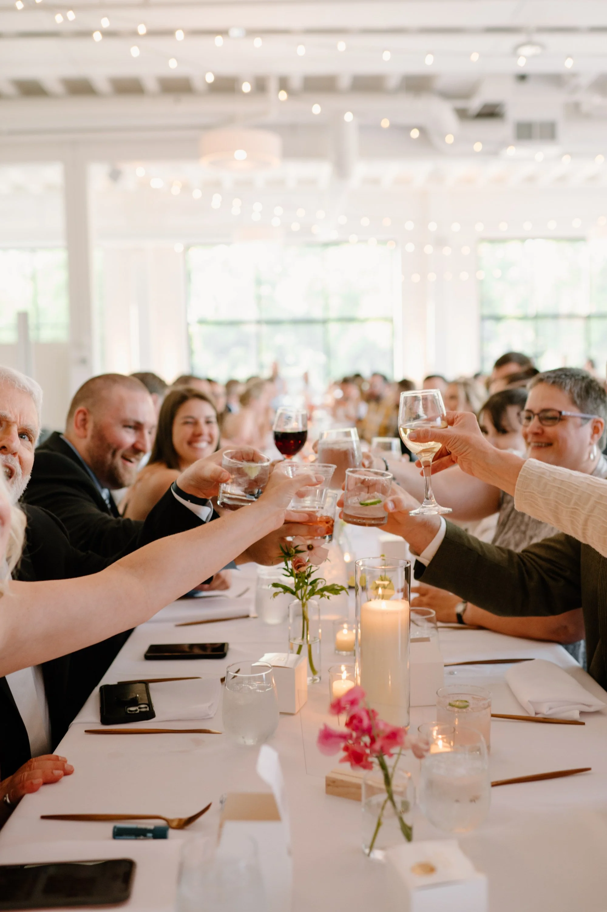 People at a wedding or celebration toast with wine and drinks at a table