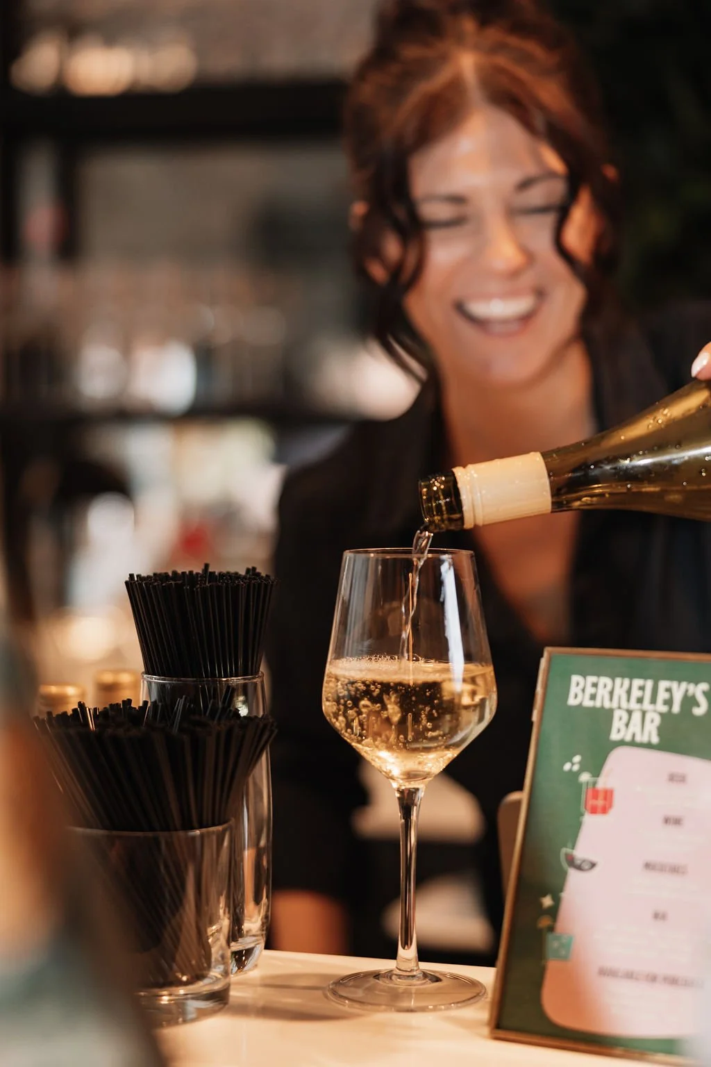 friendly, professional, and fun bartender pouring wine being the bar