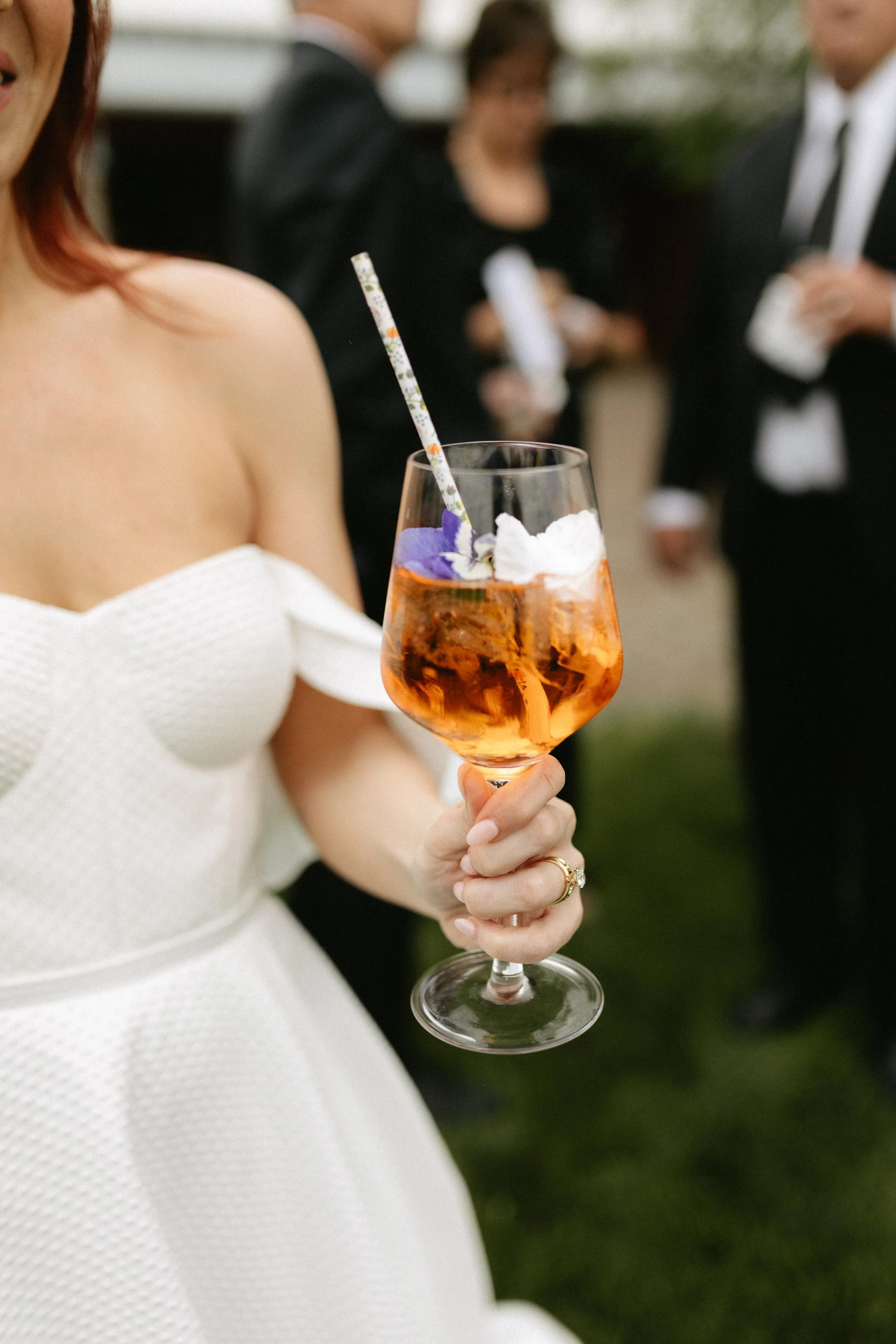 Bride with signature cocktail with an edible flower garnish
