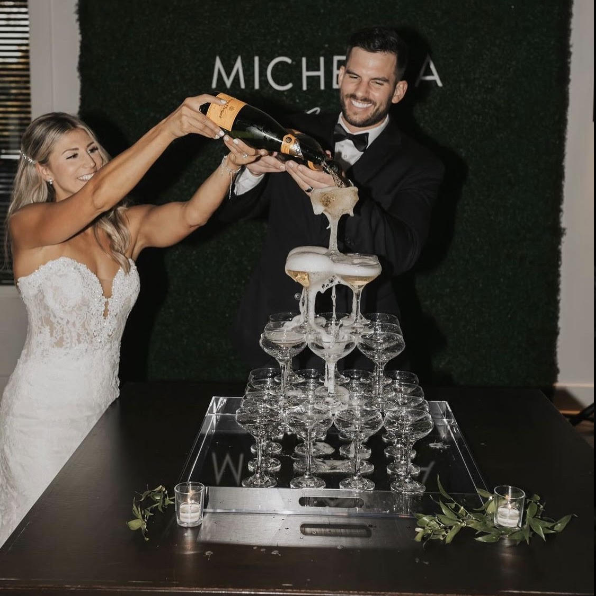 A newlywed couple is celebrating their wedding with a 30 glass champagne tower