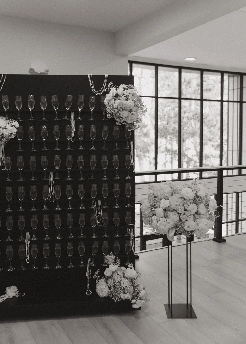 Black champagne wall with floral arrangements and pearl necklaces