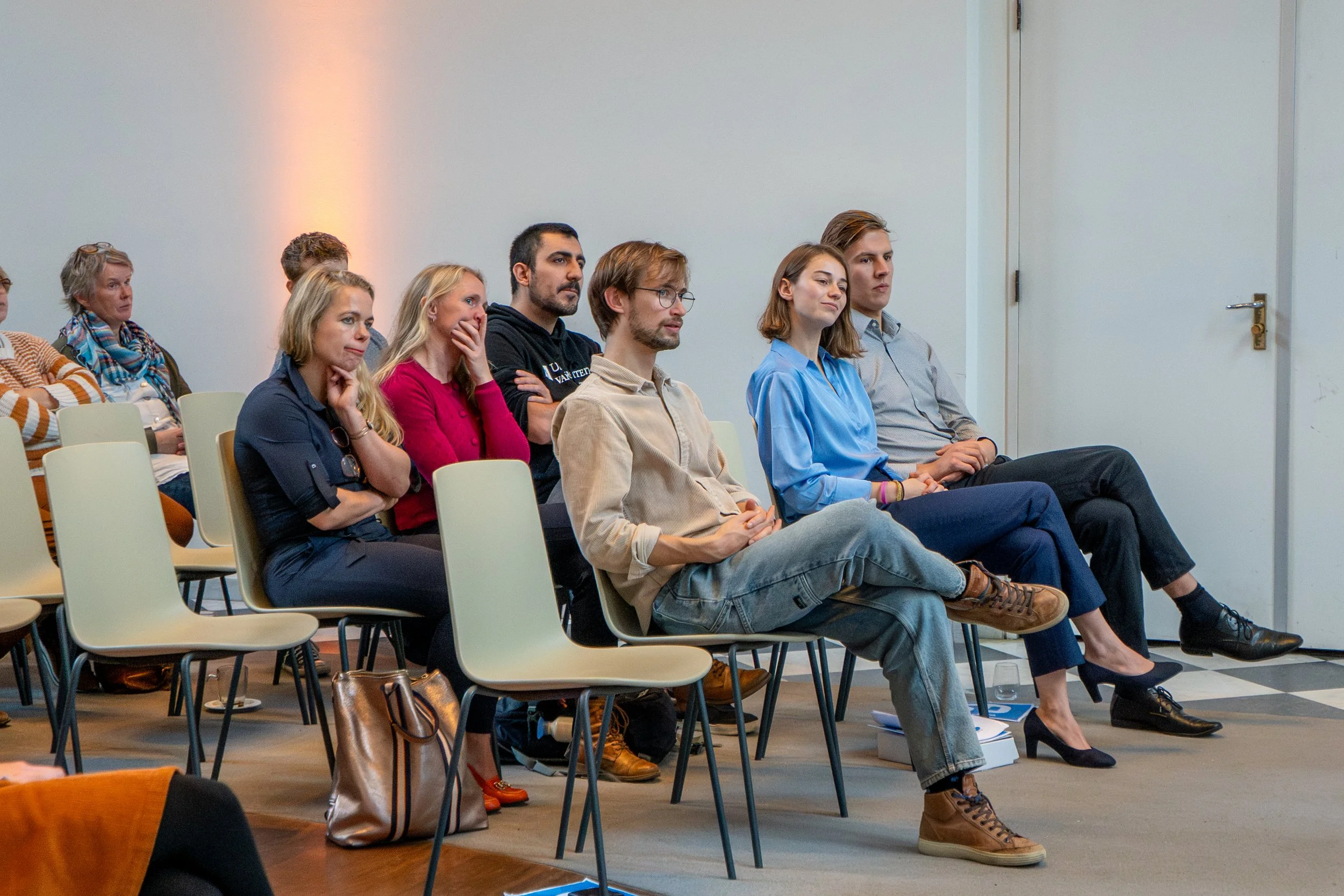 Audience seated indoors, attentively listening to a presentation or speaker.