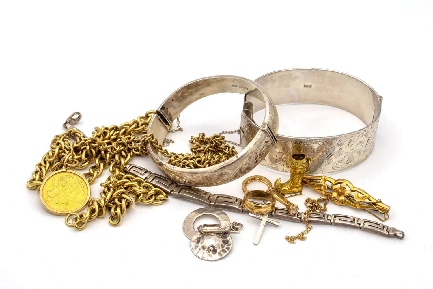 Assortment of jewelry, including large silver and gold bracelets, a gold chain with a coin, rings, earrings, and other gold and silver accessories.