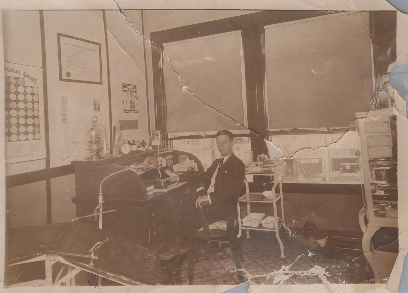 Torn, faded c. 1930 image of doctor in office.
