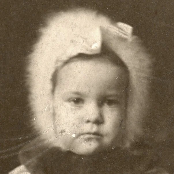 Black and white portrait of a young girl with a bow in her hair.