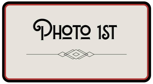 A sign that reads 'PHOTO 1ST' with decorative lines and a diamond shape in the center, framed by a red and black border.