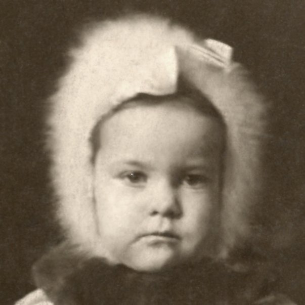 Black-and-white vintage portrait of a young girl wearing a wool hat with a bow, looking serious.