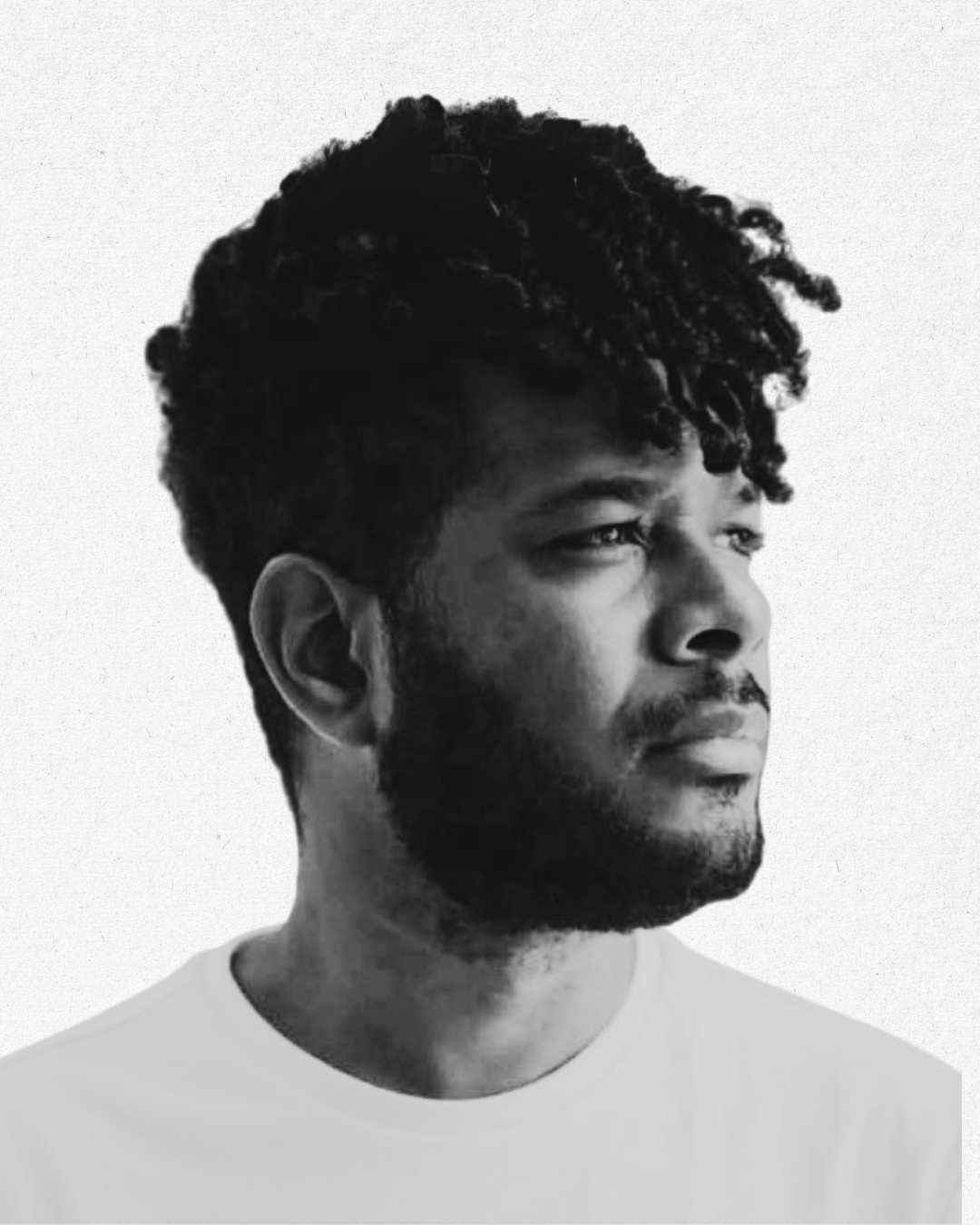 Black and white portrait of a man with textured hair, looking pensively to the right, wearing a light-colored shirt.