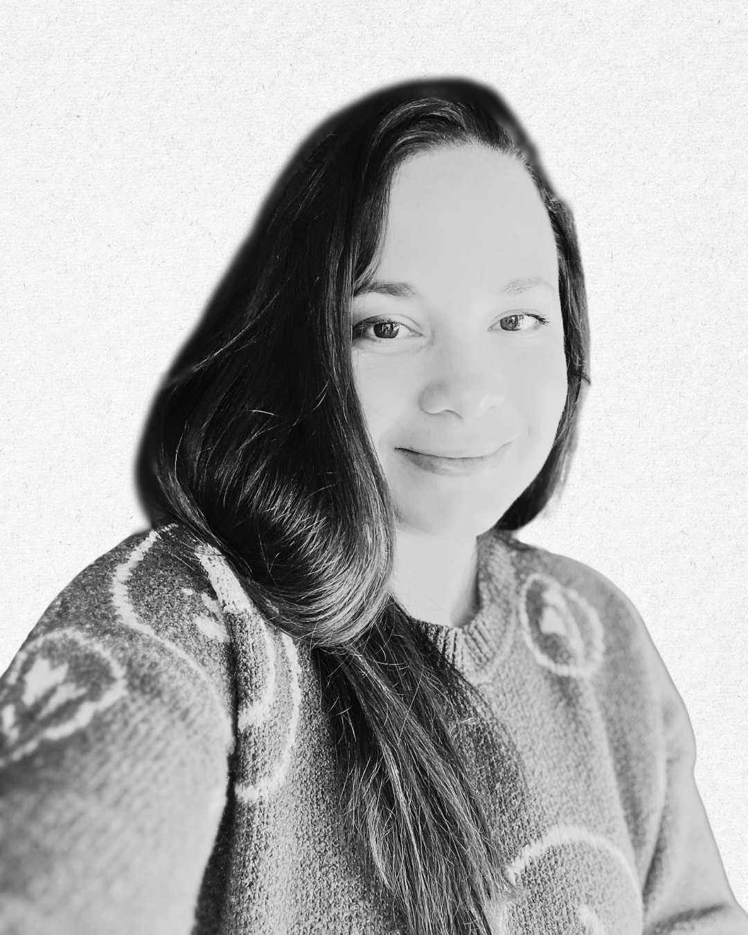 Black and white portrait of a smiling woman with long wavy hair, wearing a patterned sweater, against a plain background.