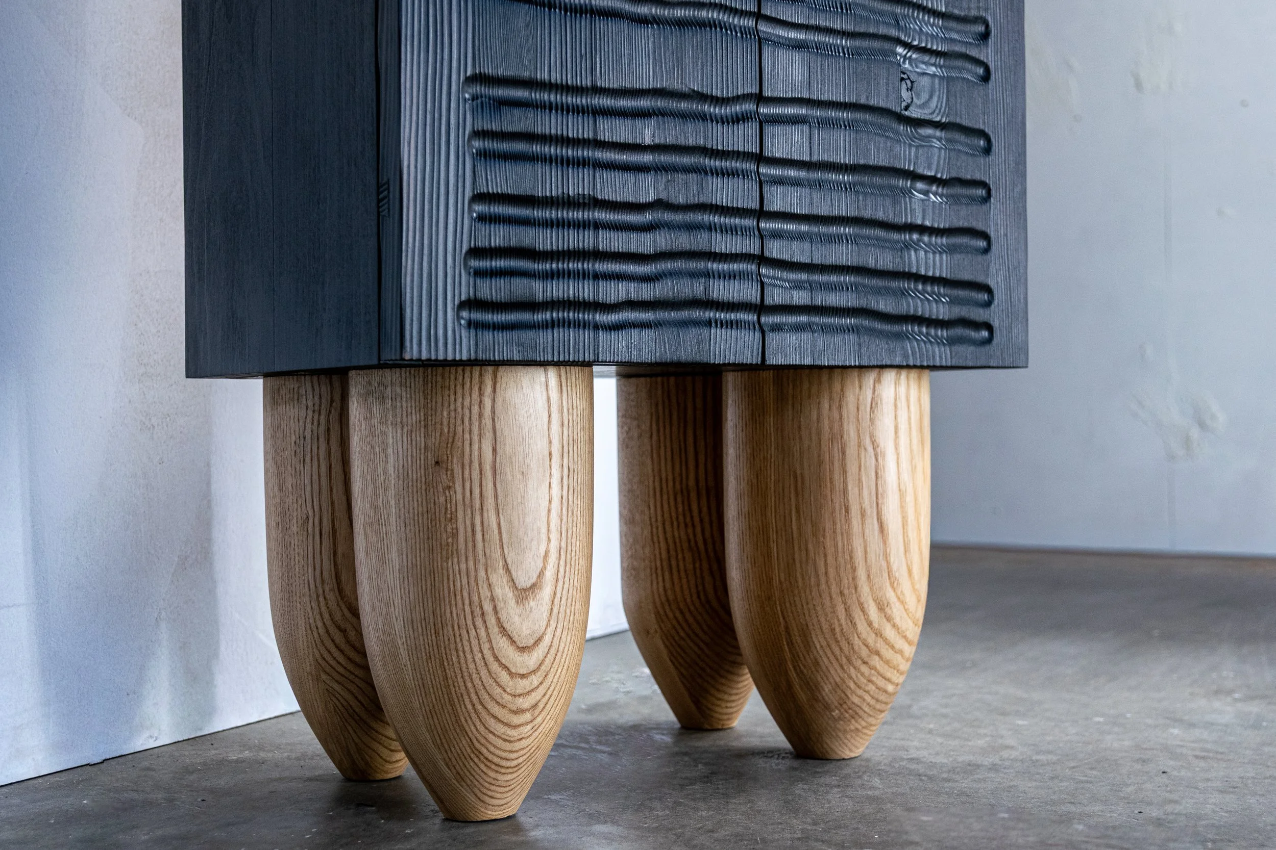 Close up of large diameter cabinet legs made of ash wood.