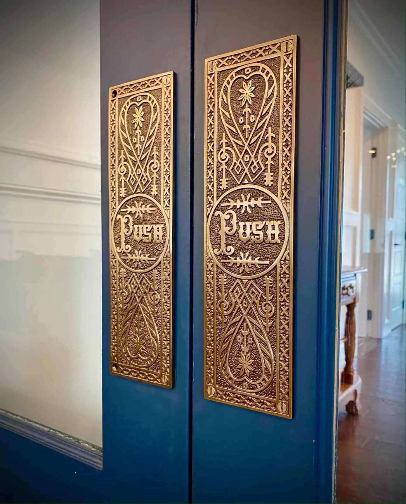 Decorative brass door push plates with "Push" text on blue doors.