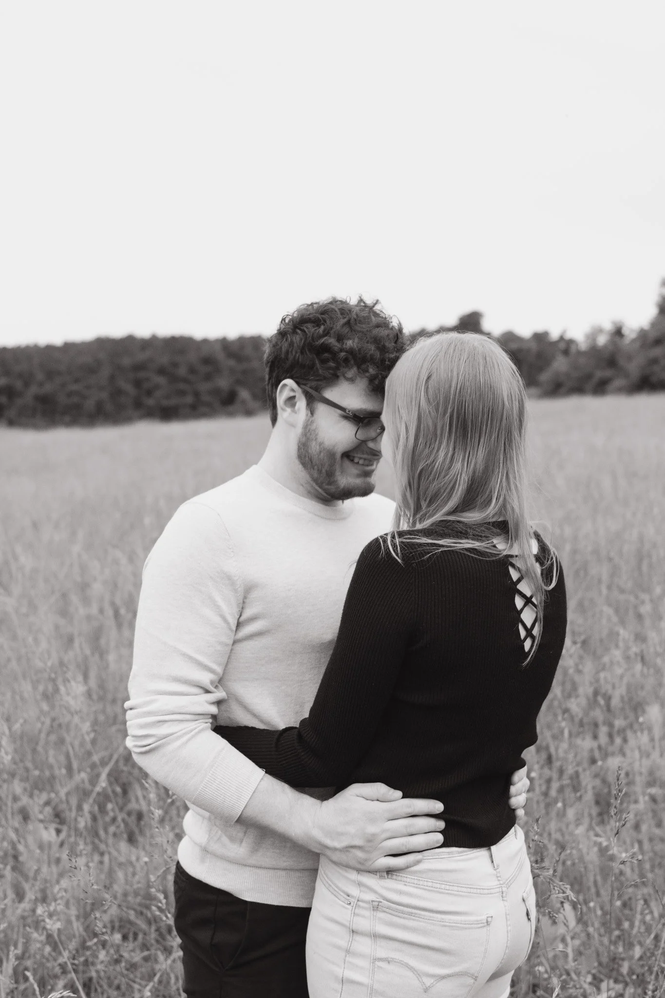 Monochrome photo of a couple embracing in a field