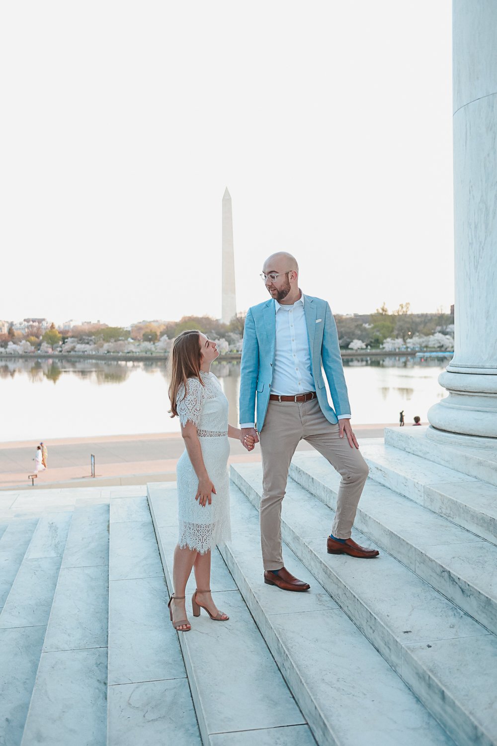 Couple on marble steps holding hands, Washington Monument in background.