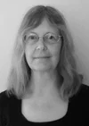 Black and white photo of a person with glasses and shoulder-length hair.