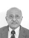 Smiling person in a suit and tie with glasses, black and white photo.