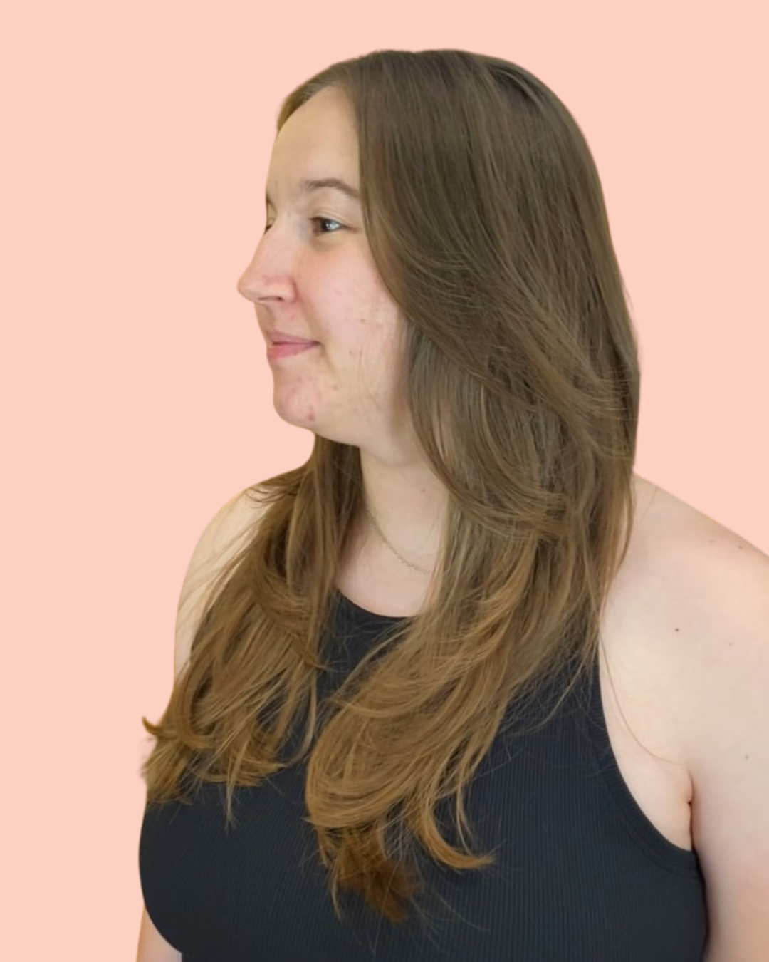 persons standing sideways in black tank top with long brown hair with layers