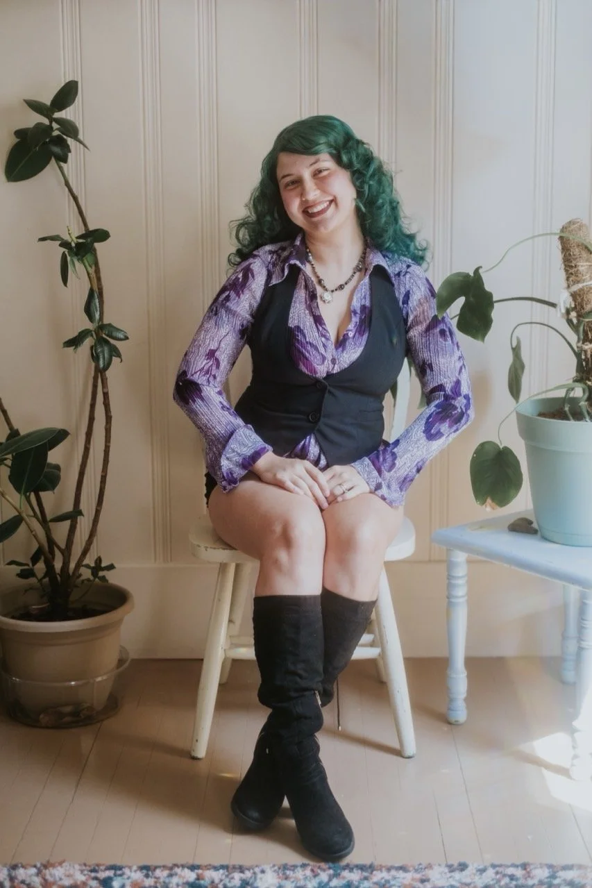 woman with green and brown hair standing in front of tree smiling at camera