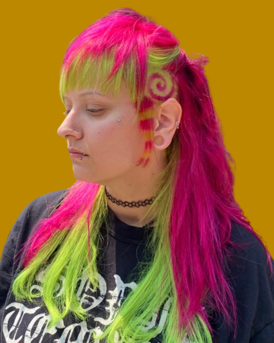 person with neon pink and green hair pulled up slightly to reveal spiral and strip color blocked hair coloring 