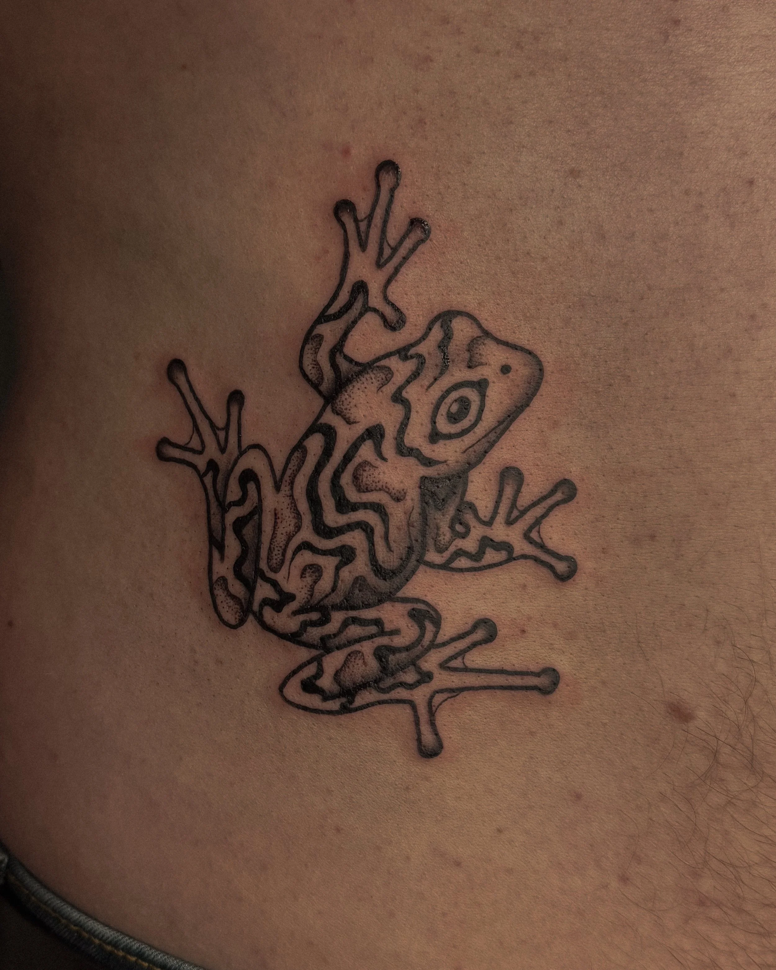 Close-up photograph of a tattoo of a stylized chameleon on a person's skin.