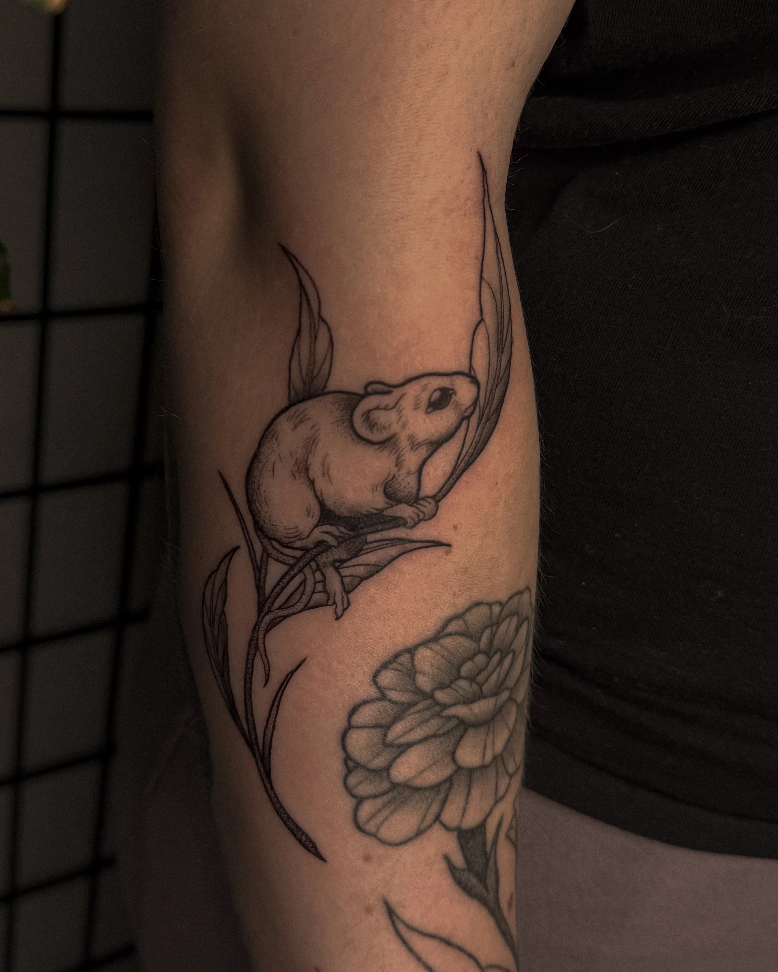 A tattoo of a deer with antlers, leaves, and flowers on the upper arm.